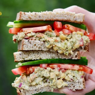 chickpea salad sandwich being held in the air