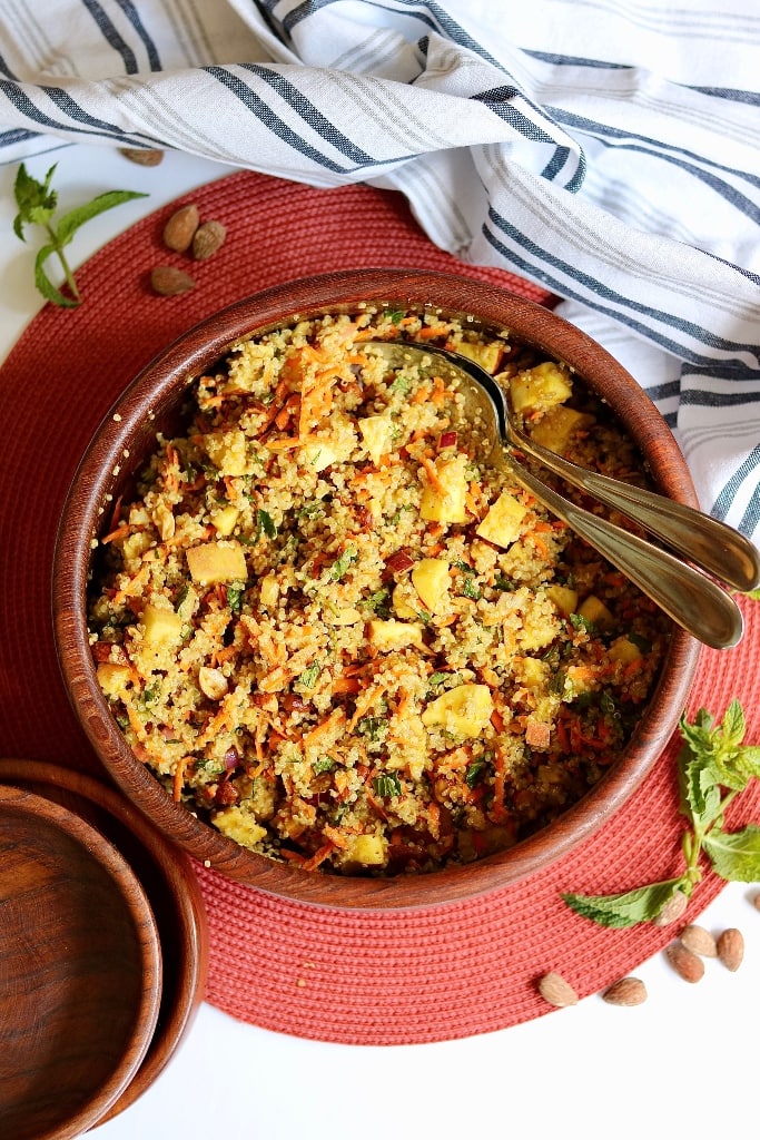 curried quinoa salad in a wooden salad bowl with serving spoons