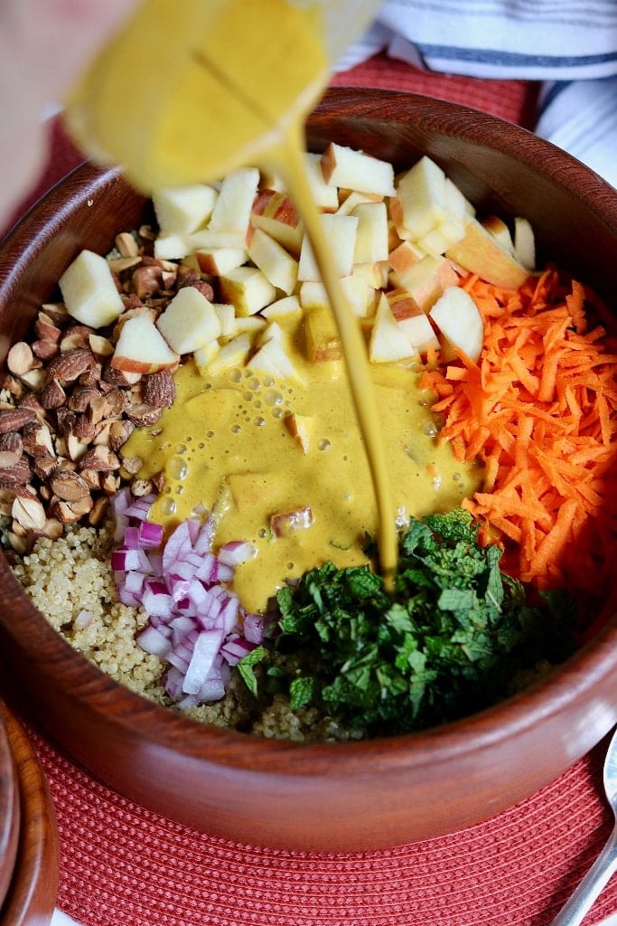 curry dressing being poured on quinoa salad