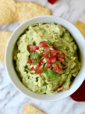 best guacamole recipe in a white bowl on a marble countertop