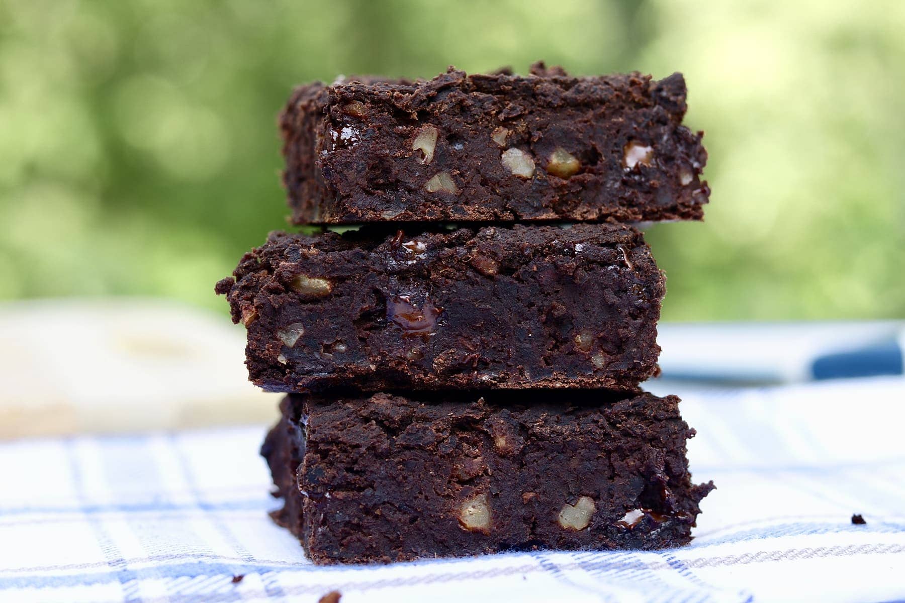 vegan black bean brownies stacked on a blue and white dishcloth