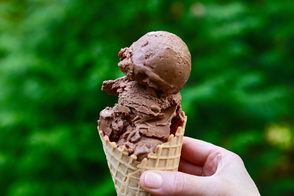 a vegan chocolate ice cream cone being held