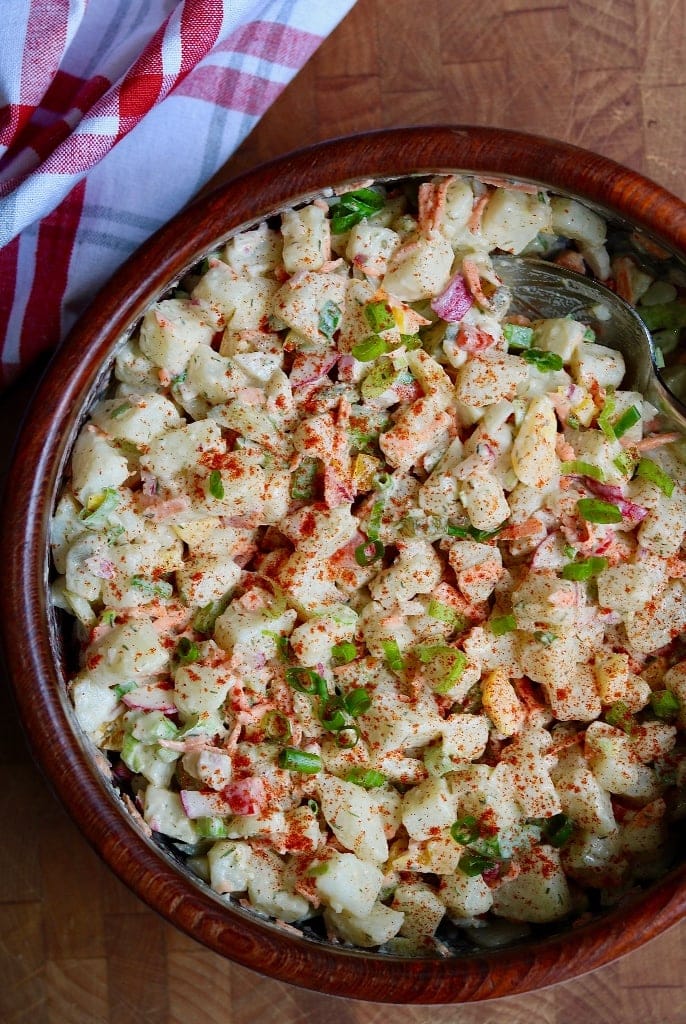 vegan potato salad in a wooden salad bowl with serving spoon