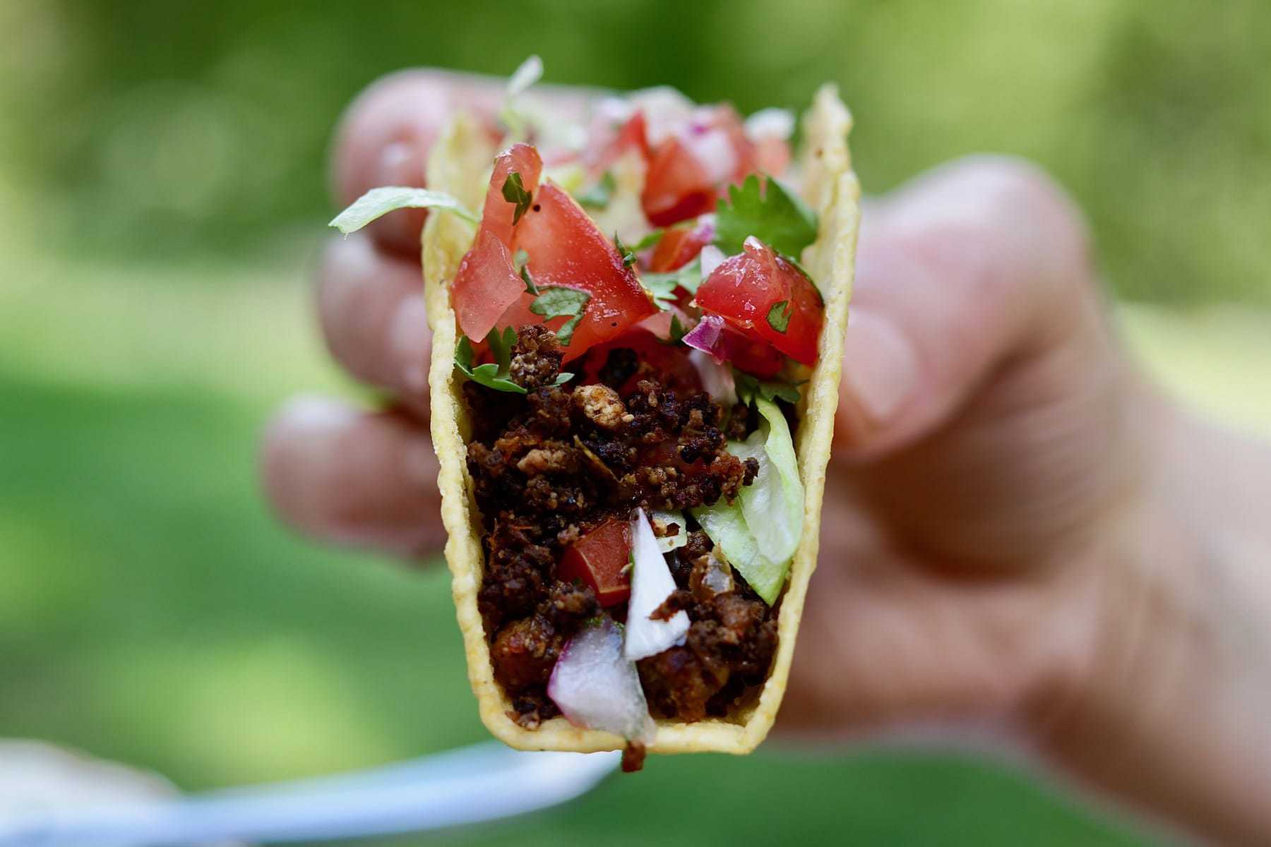 tasty tex mex vegan taco meat recipe in taco shell held in the air