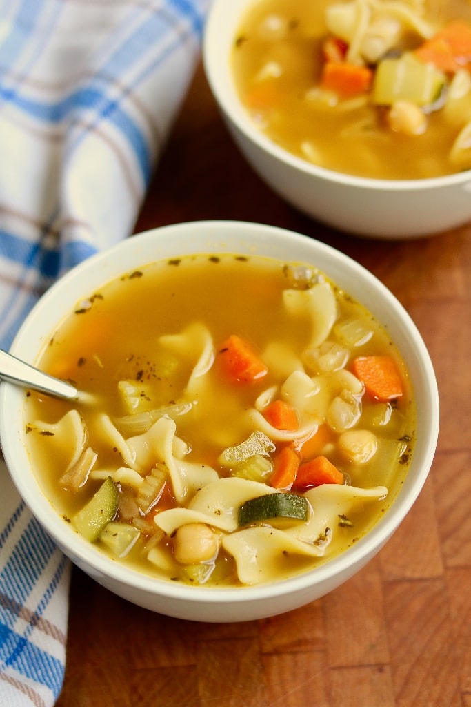 vegan chicken noodle soup in a white bowl with a spoon