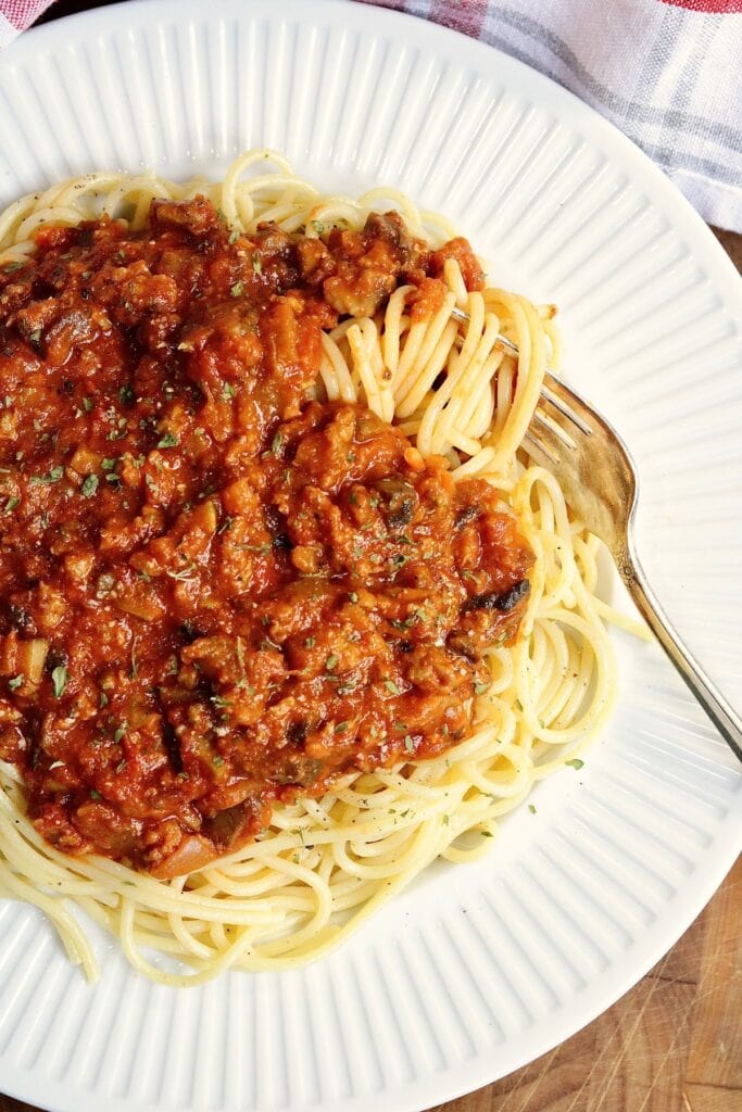 a plate of vegan spaghetti bolognese with a fork