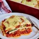 a slice of vegan lasagna on a white plate with a fork