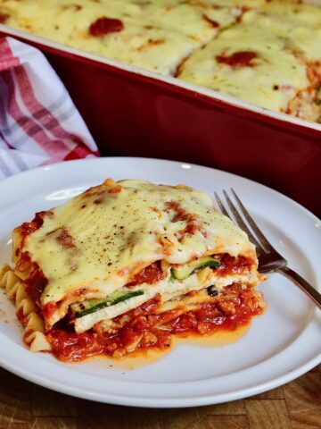 a slice of vegan lasagna on a white plate with a fork