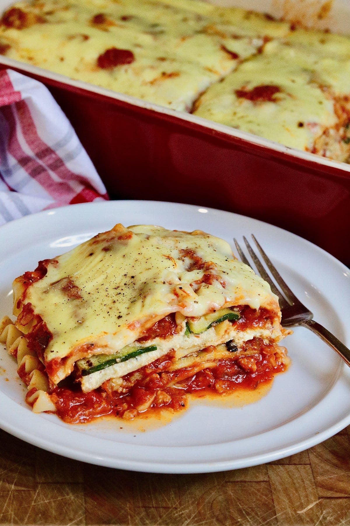 a slice of vegan lasagna on a white plate with a fork