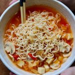 ramen noodle soup in a bowl being held with two hands