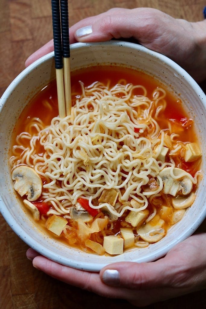 ramen noodle soup in a white bowl being held with two hands
