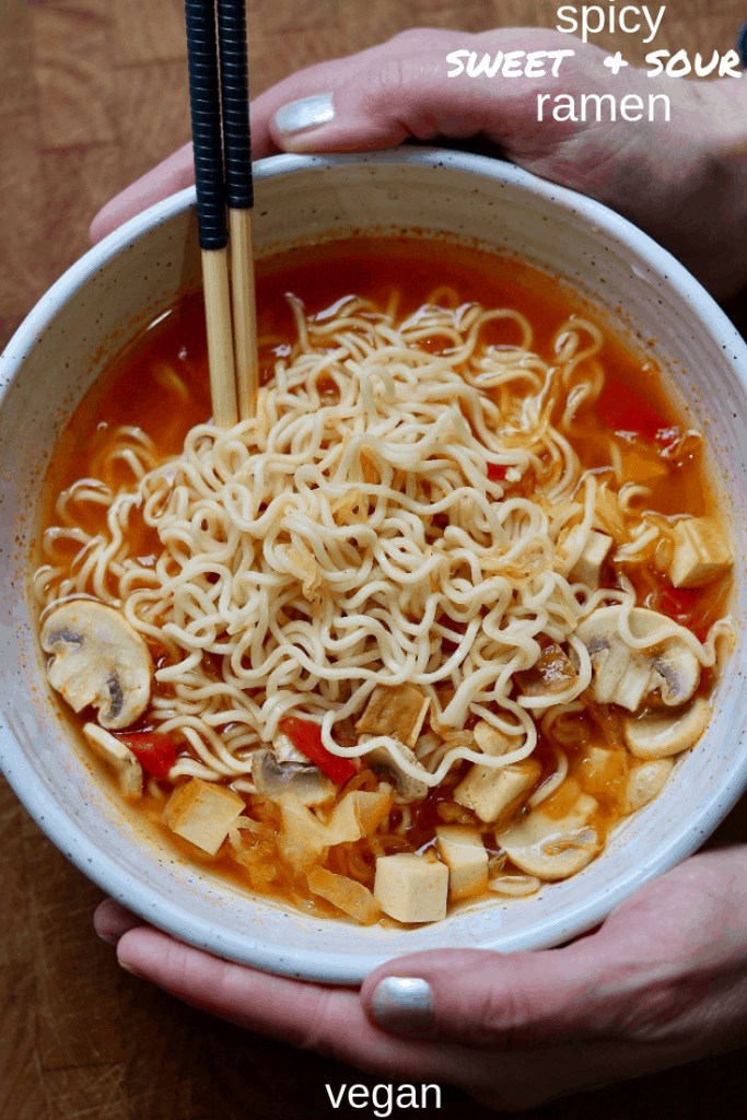 ramen noodle soup in a white bowl being held with two hands