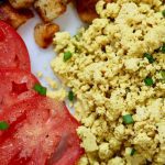 tofu scrambled eggs on a white plate with potatoes and tomatoes