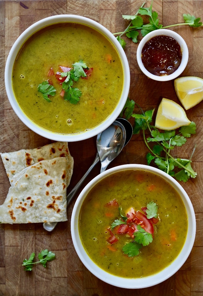 two bowls of mulligatawny soup on a wooden table 
