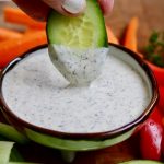cucumber slice being dipped in vegan ranch dressing