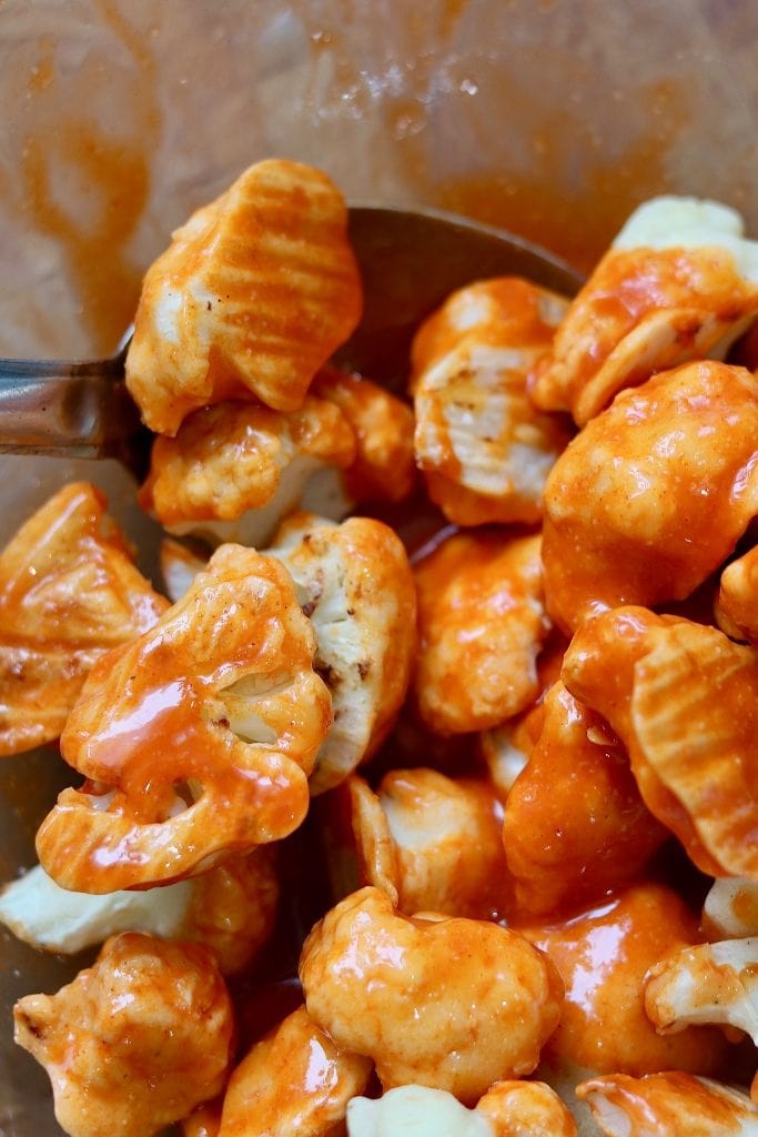 cauliflower buffalo wings in a bowl being tossed with hot sauce