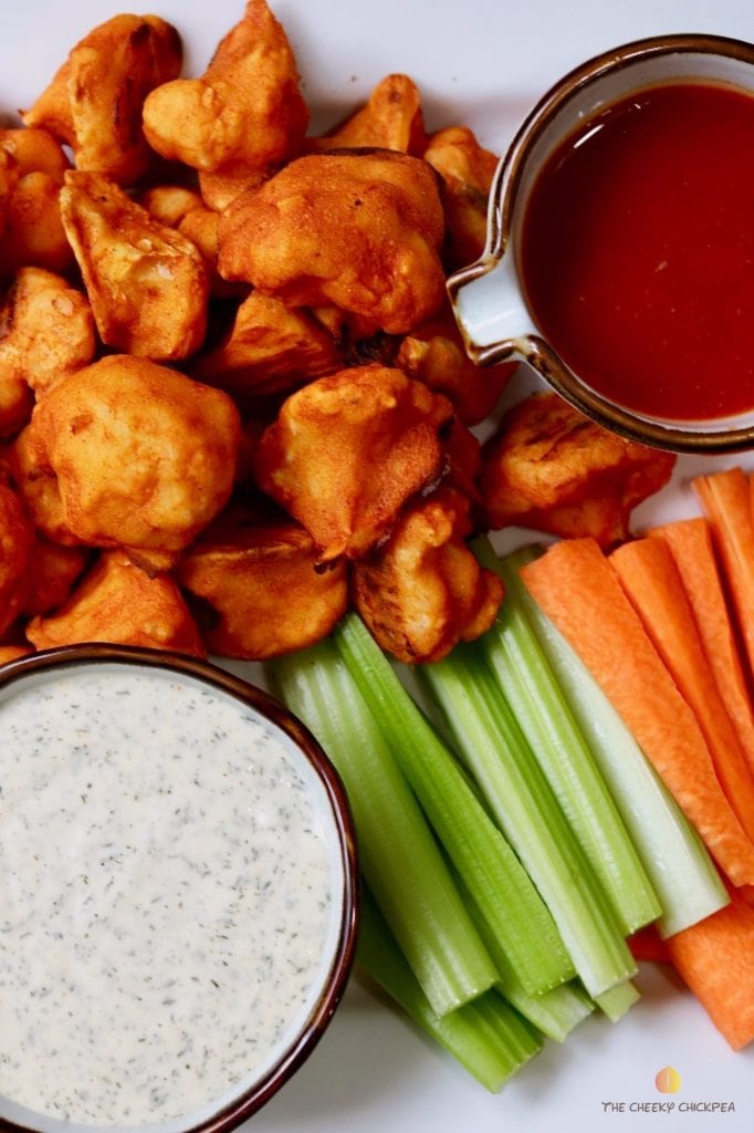 cauliflower buffalo wings on a platter with carrots celery and two dips