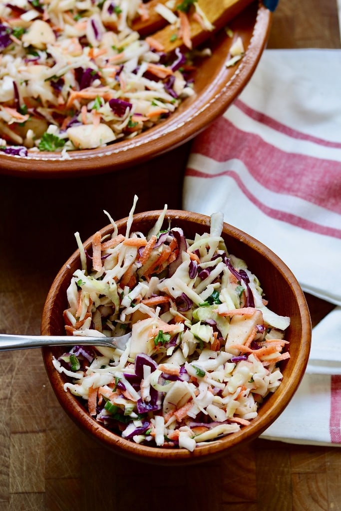classic vegan coleslaw in a wooden bowl with a fork