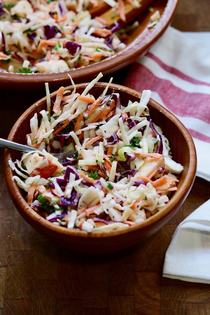 classic vegan coleslaw in a wooden bowl with a fork