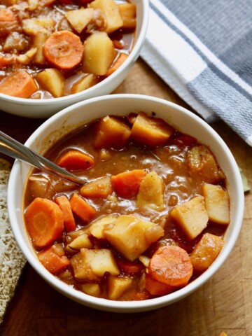 hearty vegan stew in a white bowl with a spoon