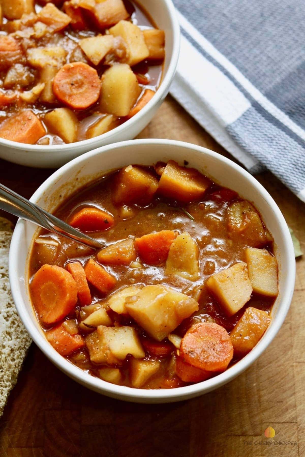 hearty vegan stew in a white bowl with a spoon