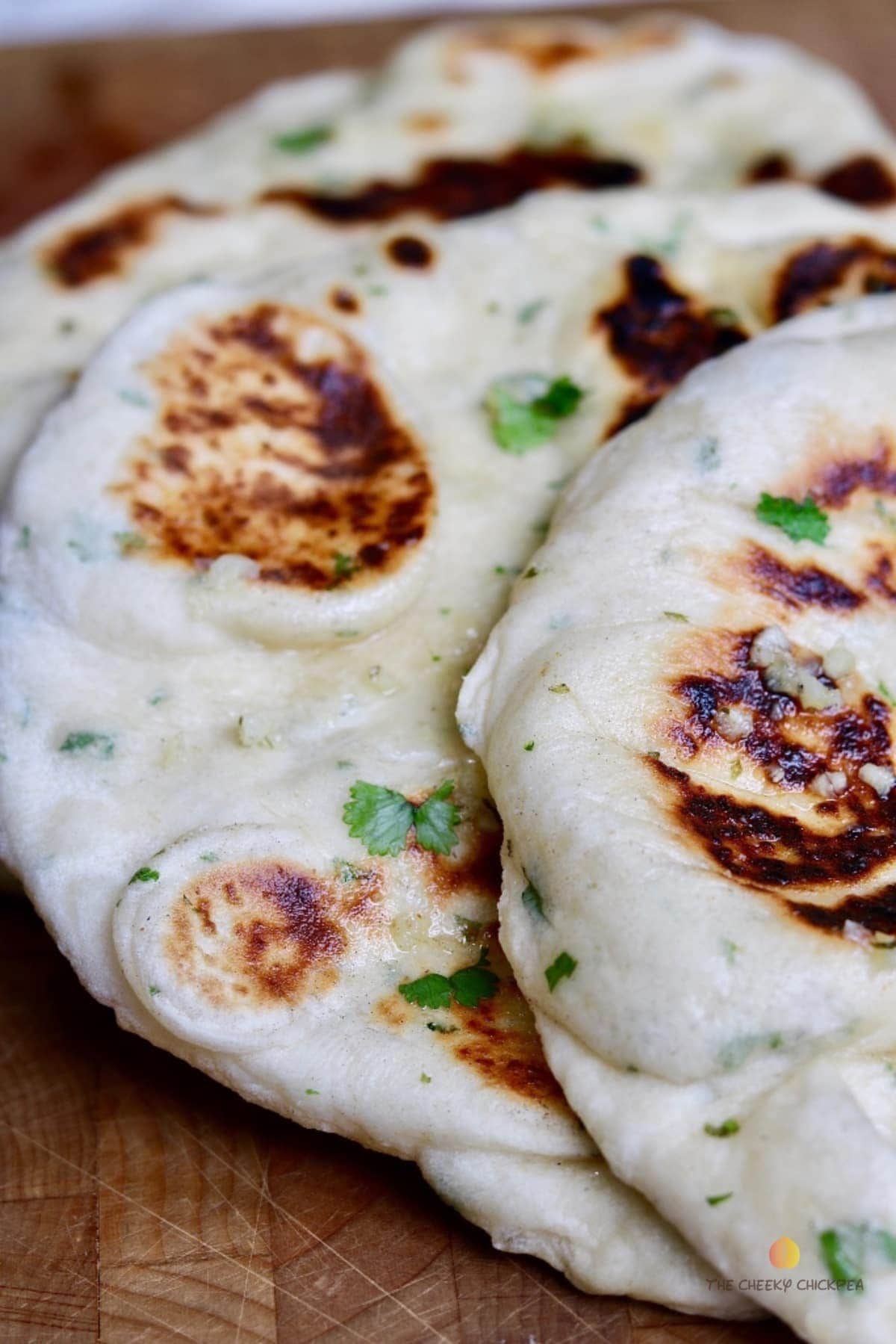 close up of two vegan naan breads on a wooden cutting board