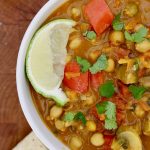 vegetable chickpea curry in a white bowl on a wooden cutting board