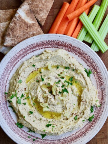 hummus in a bowl along side pita and vegetables