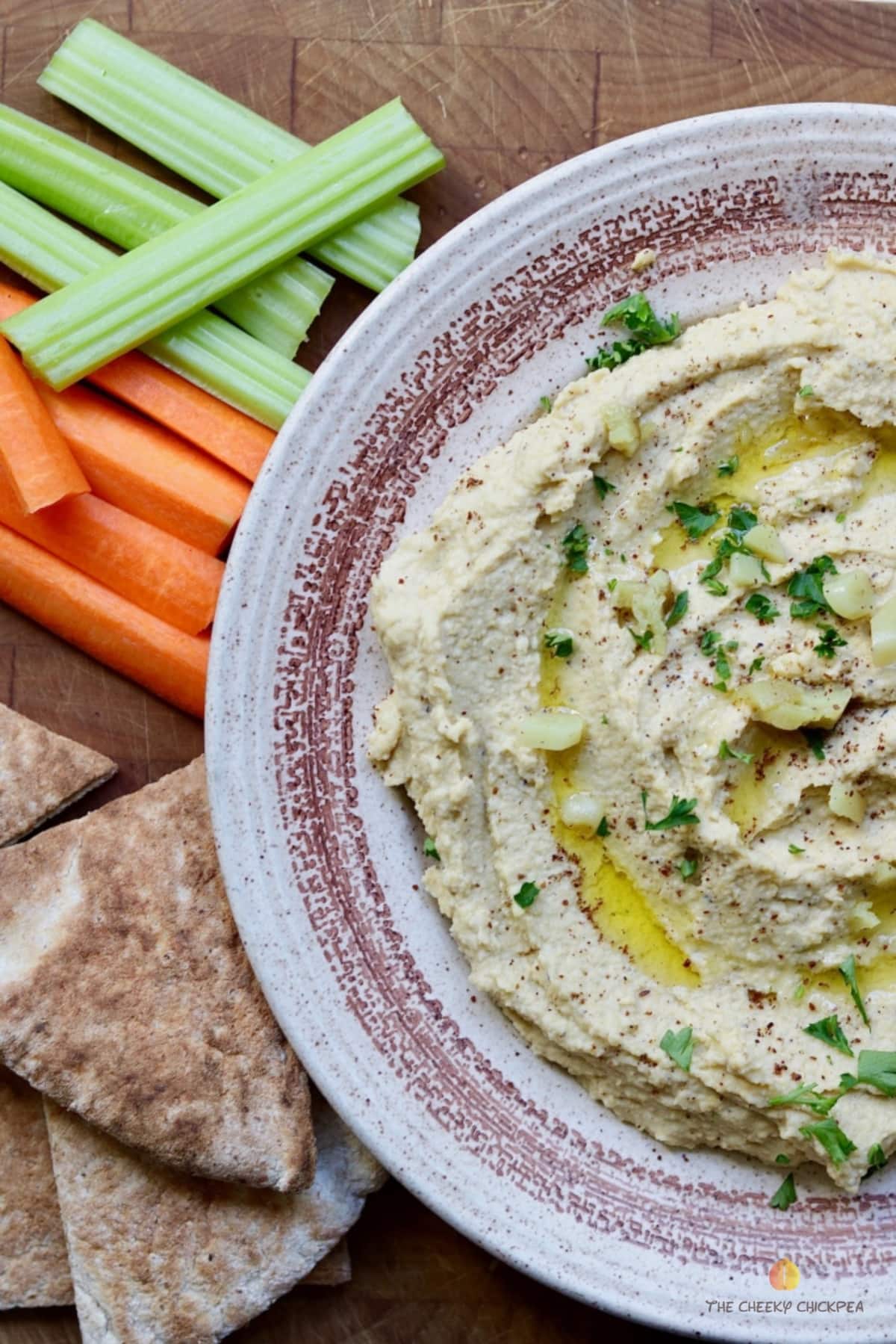 homemade hummus in a bowl along side pita and vegetables 