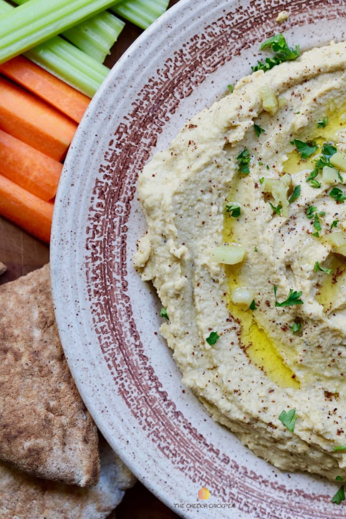 homemade hummus in a bowl along side pita and vegetables