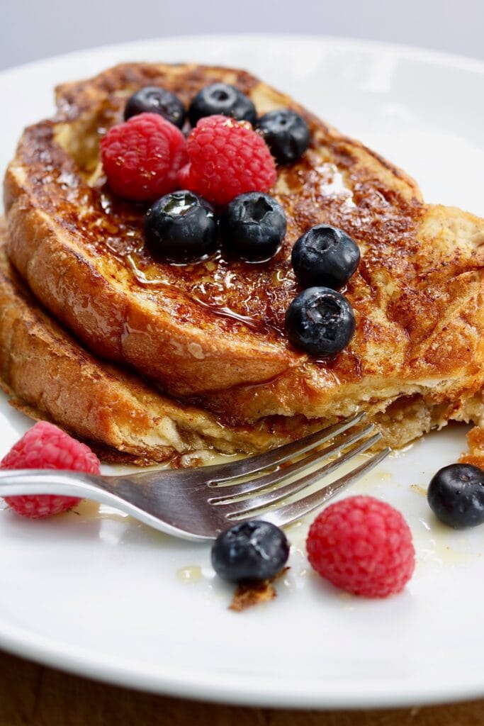 vegan french toast on a plate with maple syrup and berries