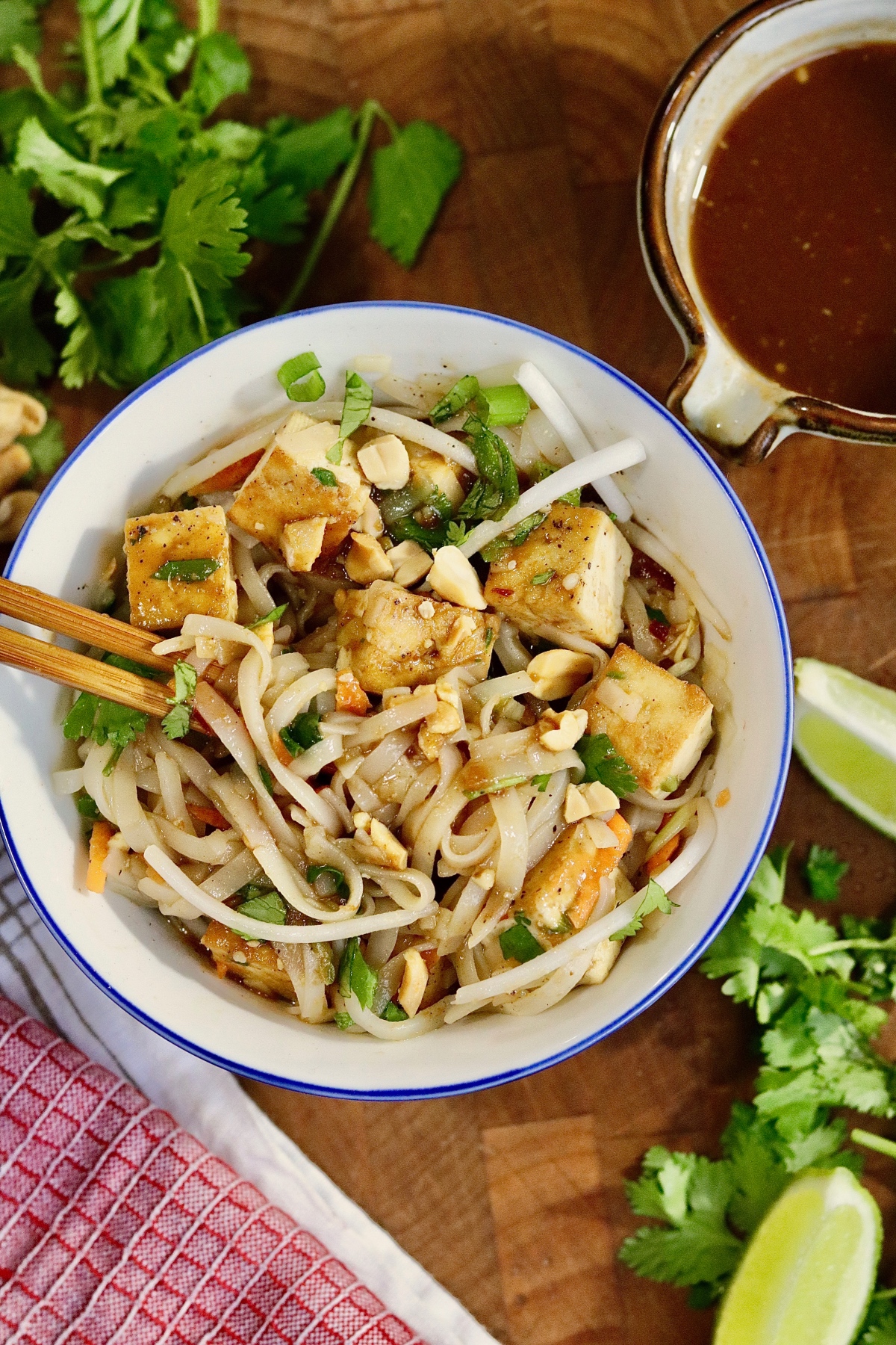 vegan pad thai in a bowl with toppings and chopsticks