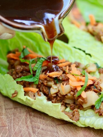 plum sauce being poured on vegetarian lettuce wrap