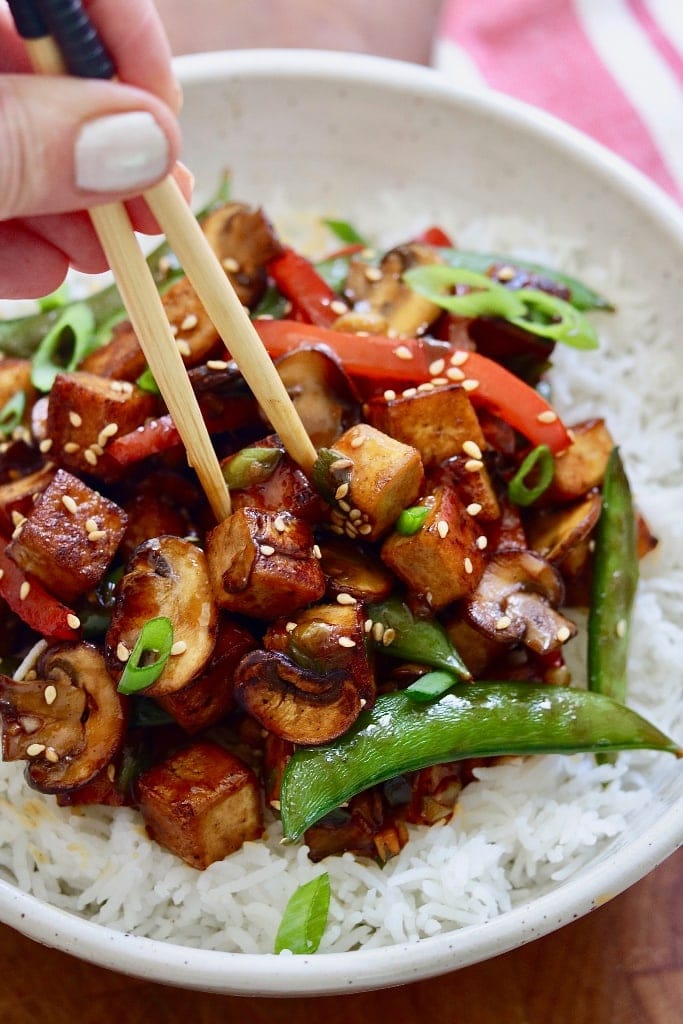 tofu stir fry in a white bowl with rice