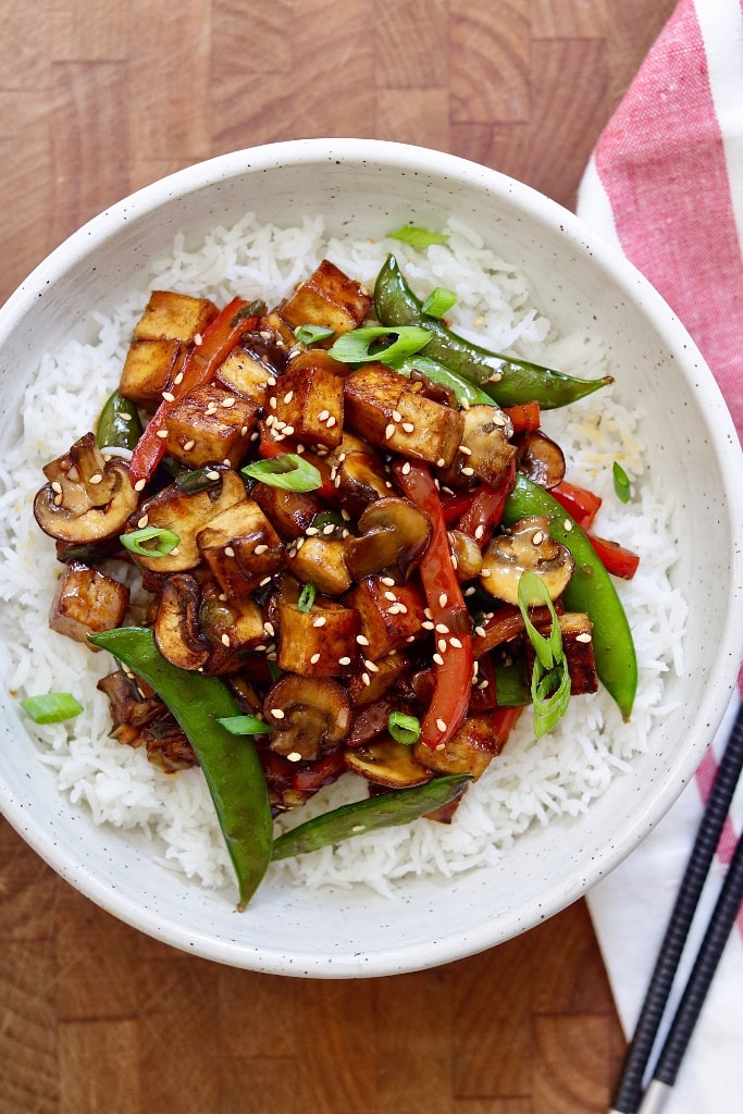 tofu stir fry served over rice in a white bowl