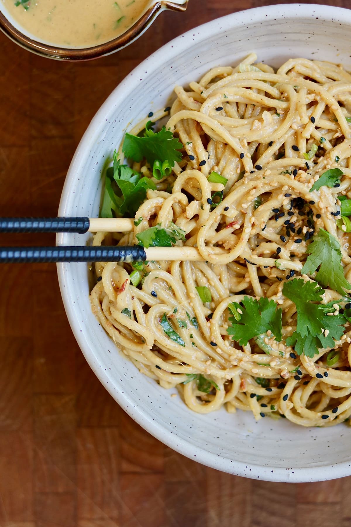 vegan peanut noodles in a bowl garnished with cilantro and sesame seeds
