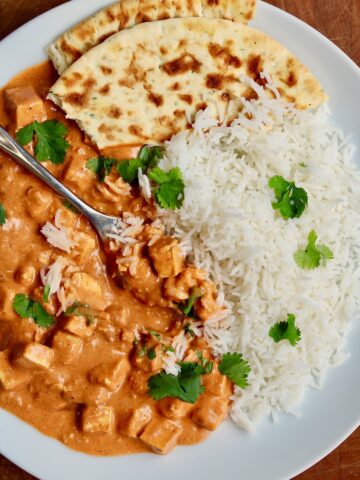 vegan butter chicken on a plate with rice and naan