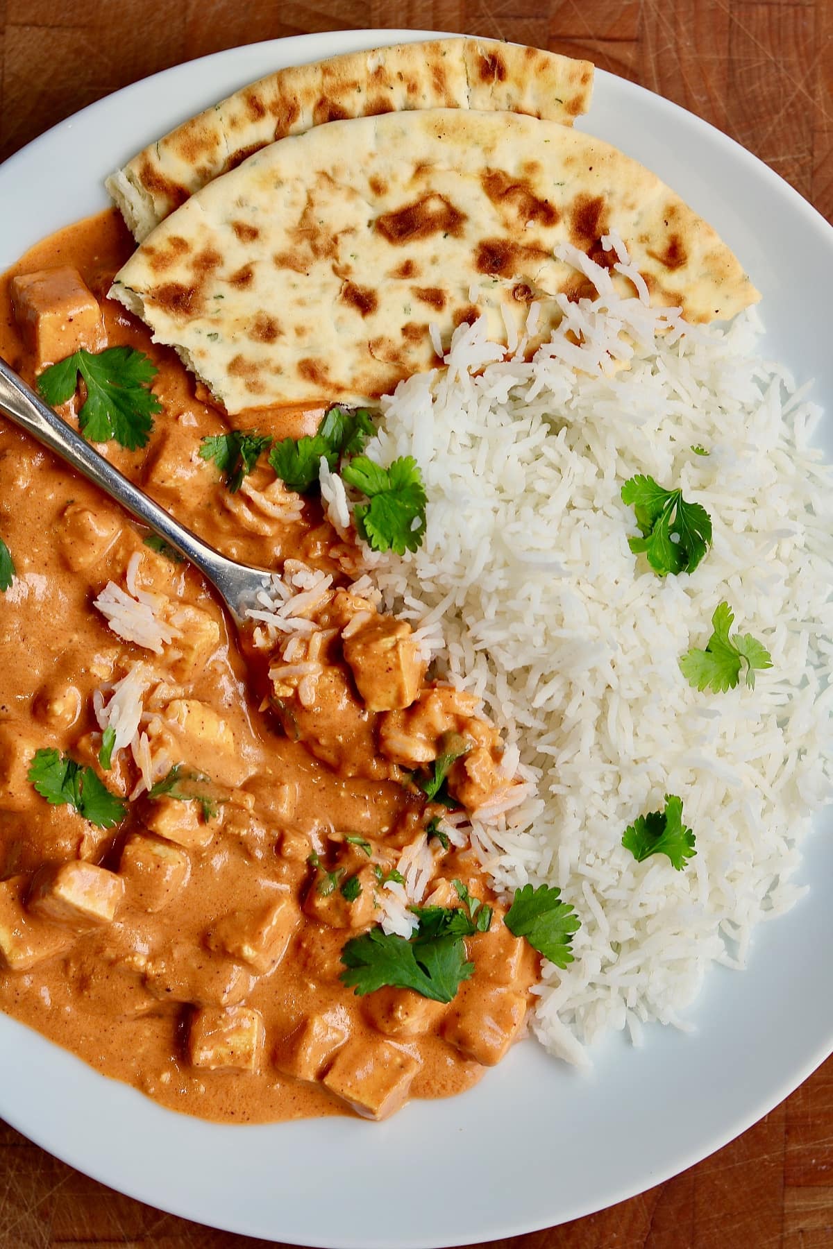 vegan butter chicken on a plate with rice and naan