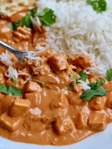 vegan butter chicken on a white plate with rice and a fork