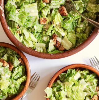 vegan caesar salad in a serving bowl and two side salad bowls