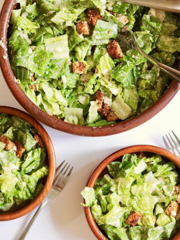 vegan caesar salad in a serving bowl and two side salad bowls