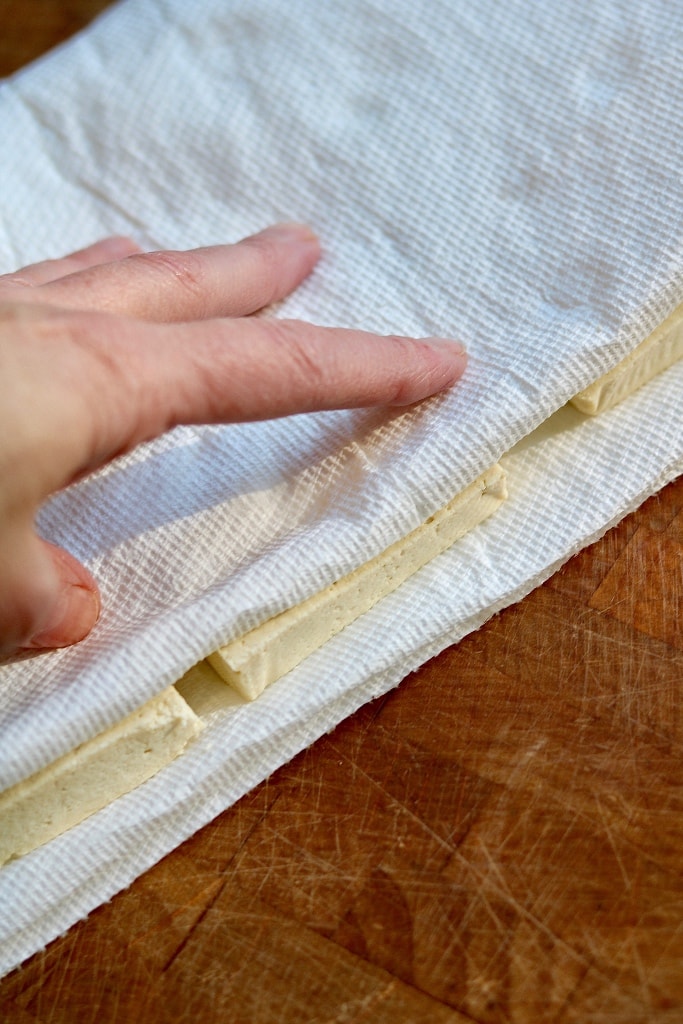 tofu being pressed with paper towel