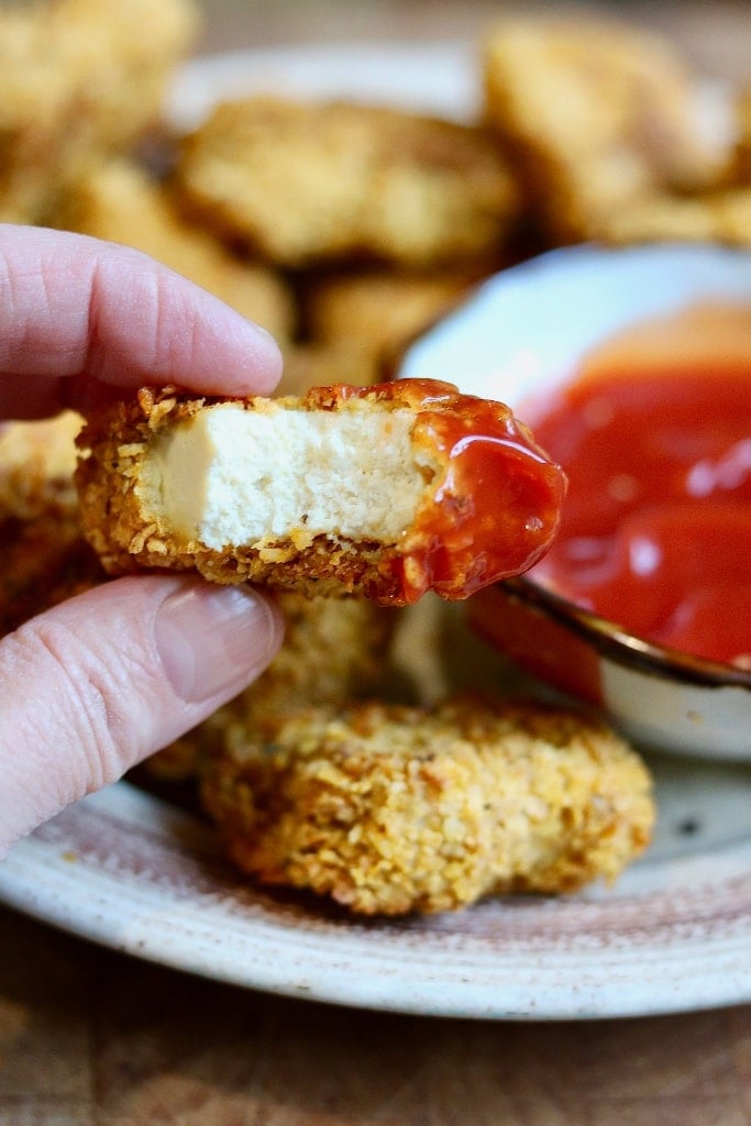 vegan chicken nugget dipped in ketchup with a bite taken out of it