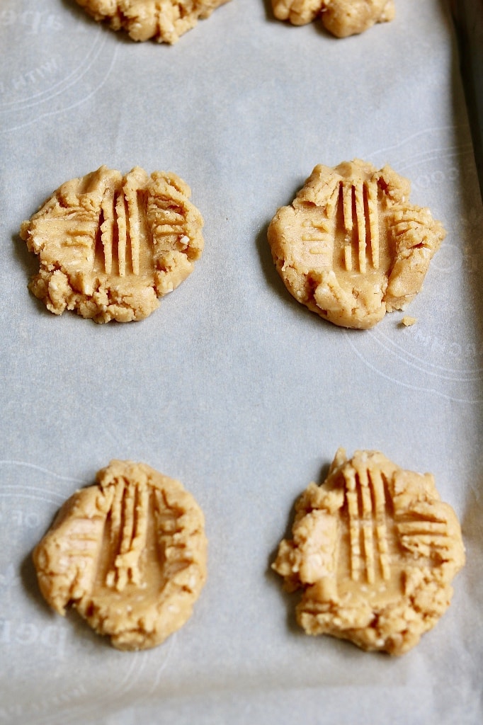 raw peanut butter cookie dough on baking sheet with criss cross patterns