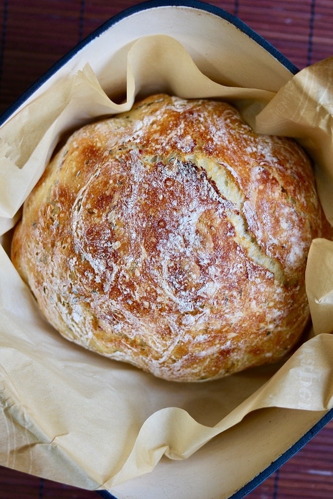 loaf of no knead bread in parchment in dutch oven