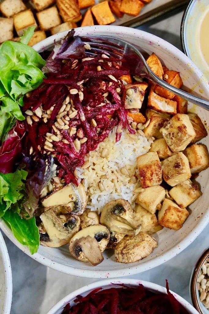 vegan buddha bowl full of veggies rice tofu and peanut dressing