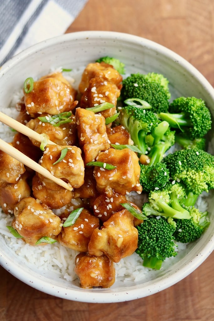 vegan orange chicken in a bowl with broccoli rice and chopsticks