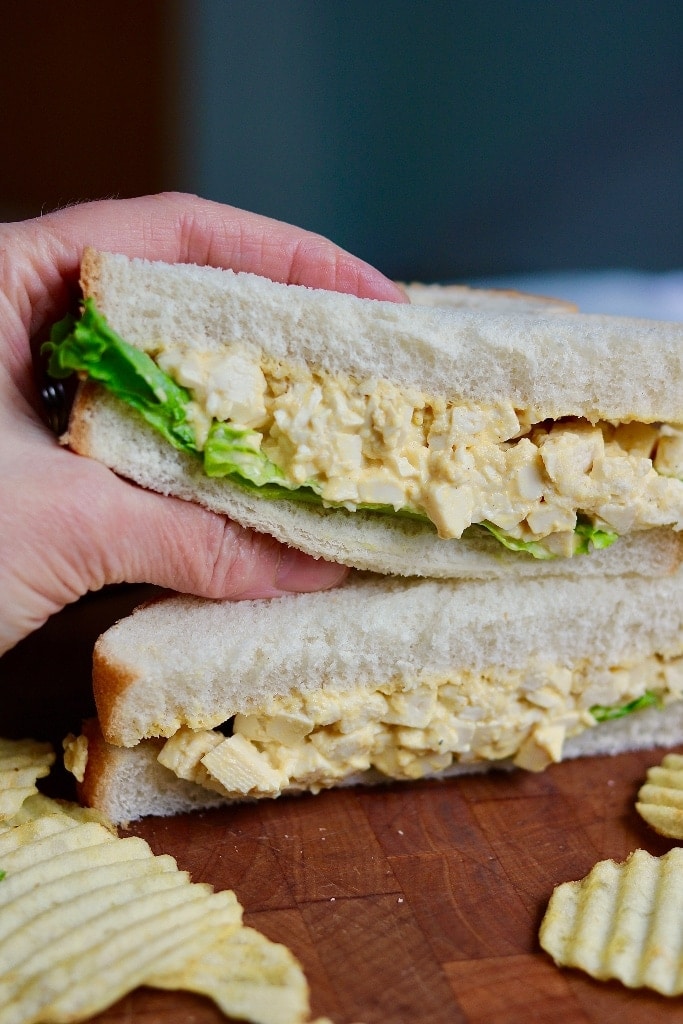 half a vegan egg salad sandwich being held