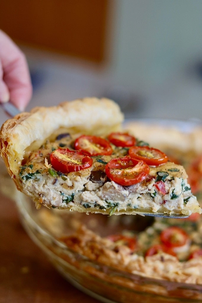 slice of vegan quiche being held in air with a pie server