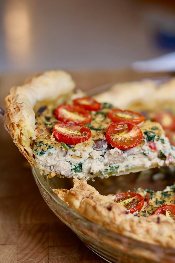 piece of vegan quiche being lifted out of pie plate